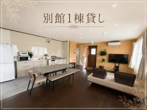 a living room with a table and a kitchen at Ryokan Seifuso in Matsumoto