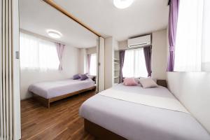 two beds in a room with two windows at HOTEL CtrlD ASAGAYA Spacious 130 Square Meter Apartment 4 Bedrooms 7 Beds 3 Minute Walk from JR Asagaya Station in Tokyo