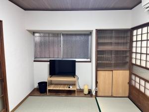 a living room with a tv and two windows at 御宿空蝉 in Tokyo