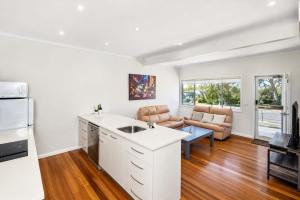 a kitchen with a sink and a living room at Harbour Breeze - apartment in Ulladulla in Ulladulla