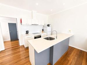 a white kitchen with a sink and a counter at Harbour Breeze - apartment in Ulladulla in Ulladulla