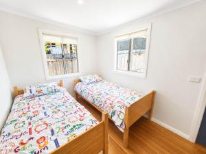 a bedroom with two beds and two windows at Harbour Breeze - apartment in Ulladulla in Ulladulla +5 photos
