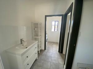 a white bathroom with a sink and a mirror at Stunning sea views & golf course in Penneshaw +16 photos