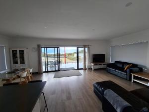 a large living room with a couch and a tv at Stunning sea views & golf course in Penneshaw