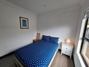 a bedroom with a blue bed and a window at Stunning sea views & golf course in Penneshaw