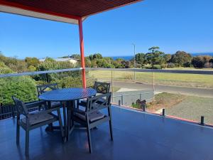 a table and chairs on a balcony with a view of a field at Stunning sea views & golf course in Penneshaw