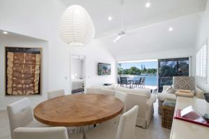 a dining room with a wooden table and white chairs at Noosa Haven Apt 12 Riverfront Elegance in Noosaville