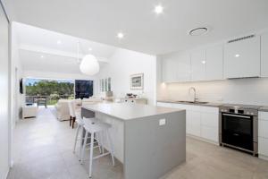 a kitchen with white cabinets and a large island at Noosa Haven Apt 12 Riverfront Elegance in Noosaville