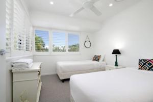 a white bedroom with two beds and a couch at Noosa Haven Apt 12 Riverfront Elegance in Noosaville +16 photos
