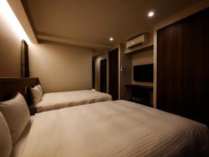 a hotel room with two beds and a television at The Hotel Chatan by Sunrest Resort in Chatan
