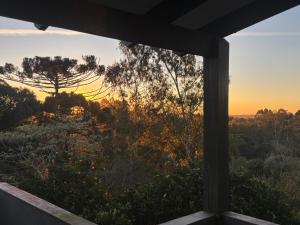 a view of the sunset from a house window at Casa vista do Vale in Farroupilha