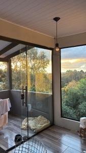 a room with a glass shower with a large window at Casa vista do Vale in Farroupilha