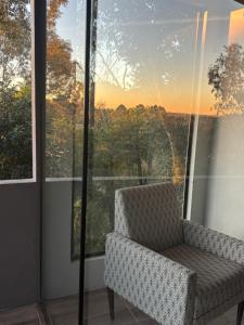 a chair in front of a window with a view at Casa vista do Vale in Farroupilha