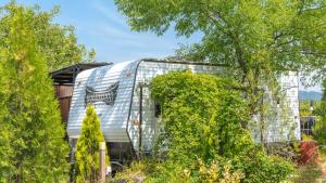 an exterior view of a silver trailer behind trees at gyeongju yongcheonsu caravan in Gyeongju