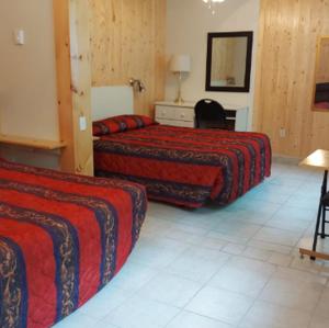 a hotel room with two beds and a mirror at Motel Sous Les Charmilles in Cap-Santé