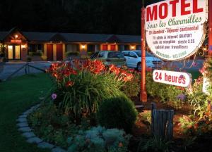 a motel sign in front of a yard with flowers at Motel Sous Les Charmilles in Cap-Santé