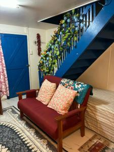 a red couch in a living room with a blue door at Raiwai Cozy Corner in Suva