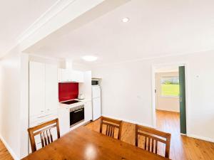 a white kitchen with a table and chairs in a room at Harbour Haven - steps from Ulladulla Harbour in Ulladulla