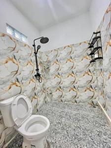 a bathroom with a toilet and a stone wall at Mahoney Homestay in Kuta Lombok