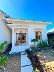 a white house with a bench in front of it at Mahoney Homestay in Kuta Lombok