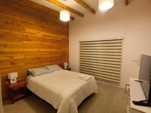 a bedroom with a bed and a wooden wall at Cabaña Lafken in Panguipulli