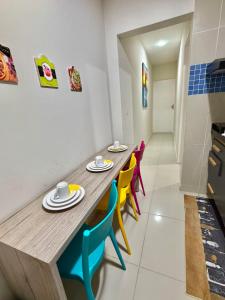 a dining room with a wooden table and colorful chairs at Flat Carneiros - Hotel Marinas in Tamandaré