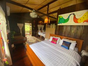 a bedroom with a bed with white sheets and colorful pillows at Elephant House and Pool Villas in Ban Sop Ao