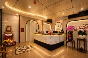 a lobby with a counter and flowers in a room at Red Sun Airport Saigon Hotel in Ho Chi Minh City