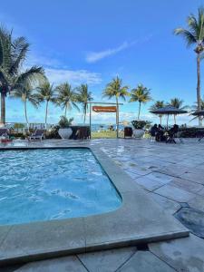 a swimming pool at a resort with palm trees at Flat Carneiros - Hotel Marinas in Tamandaré