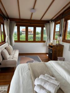a bedroom with two beds and a couch and windows at Nonnatatonview นอนนาตาทนวิว in Phayao