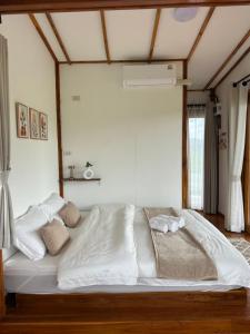 a bed with white sheets and pillows in a room at Nonnatatonview นอนนาตาทนวิว in Phayao +7 photos