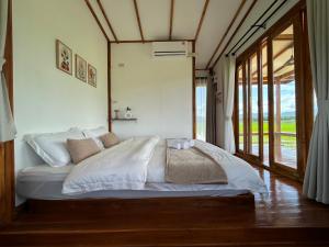a bedroom with a bed with white sheets and a window at Nonnatatonview นอนนาตาทนวิว in Phayao