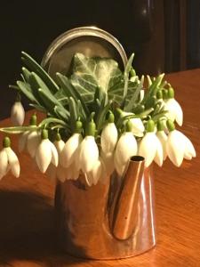 eine Metallvase mit weißen Blumen auf dem Tisch in der Unterkunft Gast in Hedwigs Haus auf dem Meere in Lüneburg