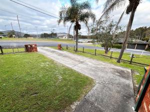 a walkway next to a street with palm trees at Chalkers Unit - Bring your own linen in South West Rocks
