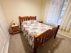 a bedroom with a bed with a floral bedspread and a window at Chalkers Unit - Bring your own linen in South West Rocks