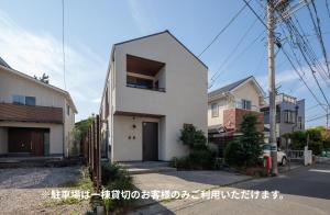 a white house with a door on a street at 材木座海水浴場まで徒歩3分 - Shell The Third-鎌倉で楽しむカリフォルニアスタイルの上質な空間 in Kamakura