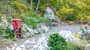a garden with a red telephone booth and white flowers at Gapyeong Pogny Kids Poolvilla in Gapyeong