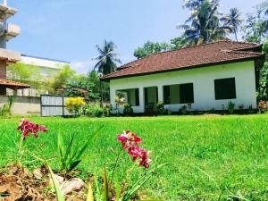 a small house in a field of grass with flowers at Villa77 Benthota in Bentota