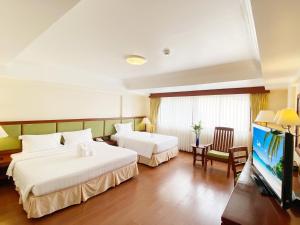 a hotel room with two beds and a flat screen tv at Kalim Resort in Patong Beach +18 photos