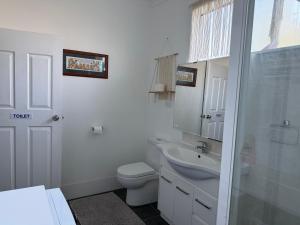 a white bathroom with a toilet and a sink at Opal St Homestay in Lightning Ridge