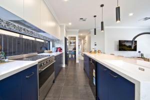 a large kitchen with blue cabinets and white counters at Serenity Place in Mannering Park