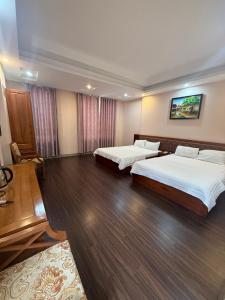 two beds in a hotel room with wooden floors at Victoria hotel in Ha Long