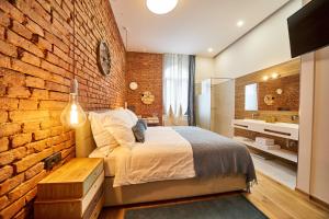 um quarto com uma parede de tijolos, uma cama e um lavatório. em Indigo Centar em Zagreb