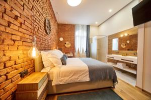 a bedroom with a brick wall and a bed and a sink at Indigo Centar in Zagreb