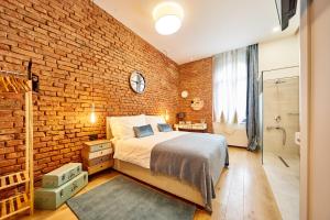 a brick walled bedroom with a bed and a bathroom at Indigo Centar in Zagreb