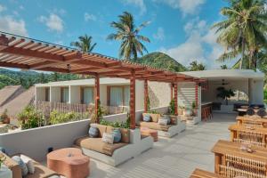 a patio with couches and tables and a pergola at Boni Beach Villas in Selong Belanak