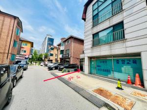 a street with cars parked next to a building at Pinkliey House in Ilsan-yŏk