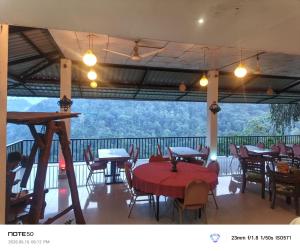 a restaurant with tables and chairs and a balcony at Adventure Manor in Kitulgala