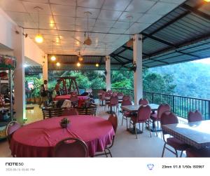 a restaurant with tables and chairs and a balcony at Adventure Manor in Kitulgala