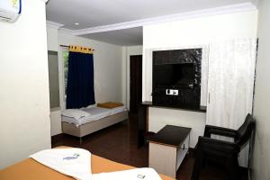 a small room with a bed and a television at Hotel Amaravathi Grand in Vijayawāda